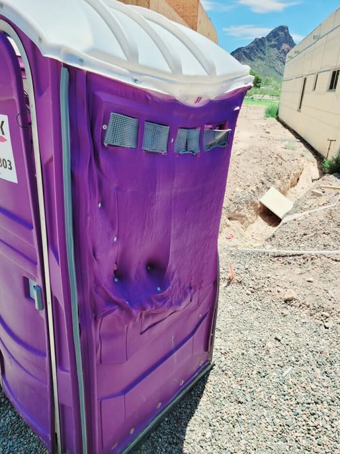 Purple portable toilet partially melted by the sun, showing the summer melting damage.