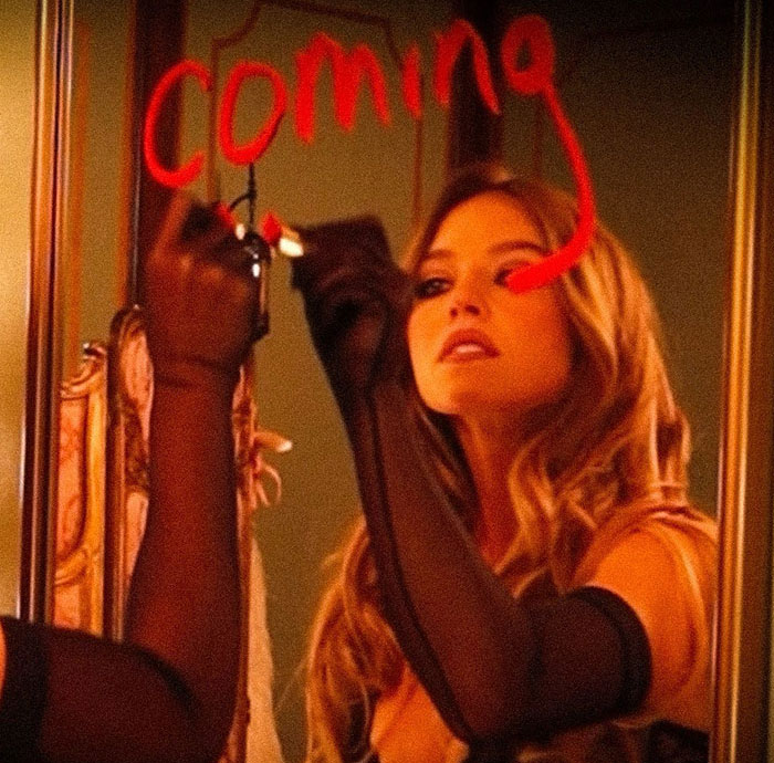 Sydney Sweeney writes on a mirror, creating a sensual scene for the SYRN lingerie video.