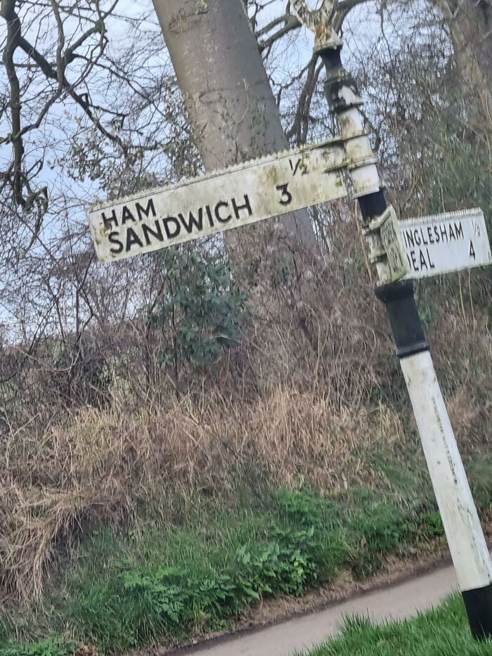 A quirky road sign pointing to Ham Sandwich in the British countryside, a perfect example of dry British humor.