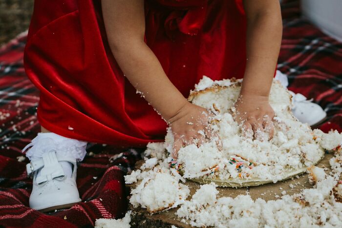 A child in a red dress smashing a wedding cake, illustrating a chaotic wedding moment.