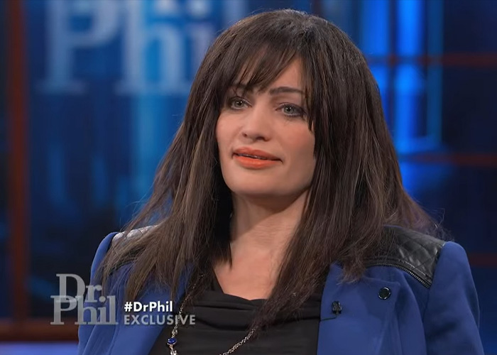 A woman with long dark hair, wearing a blue jacket and black top, appearing on Dr. Phil discussing her violent kidnapping. A woman with long dark hair, wearing a blue jacket and black top, appearing on Dr. Phil discussing her violent kidnapping.