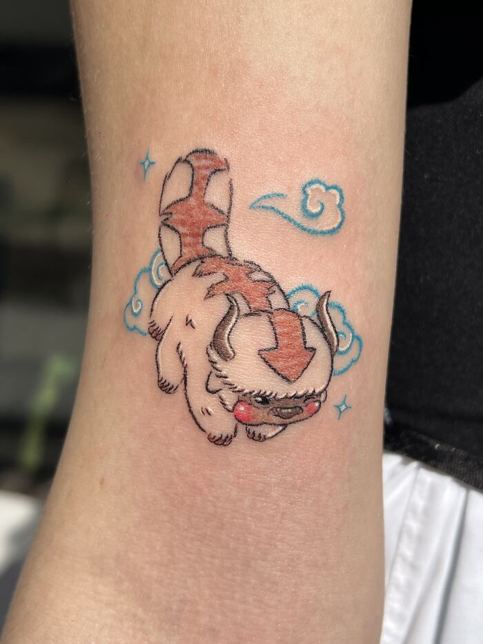 Playful Appa tattoo inspired by crayon drawings, with clouds and stars, capturing childhood creativity.