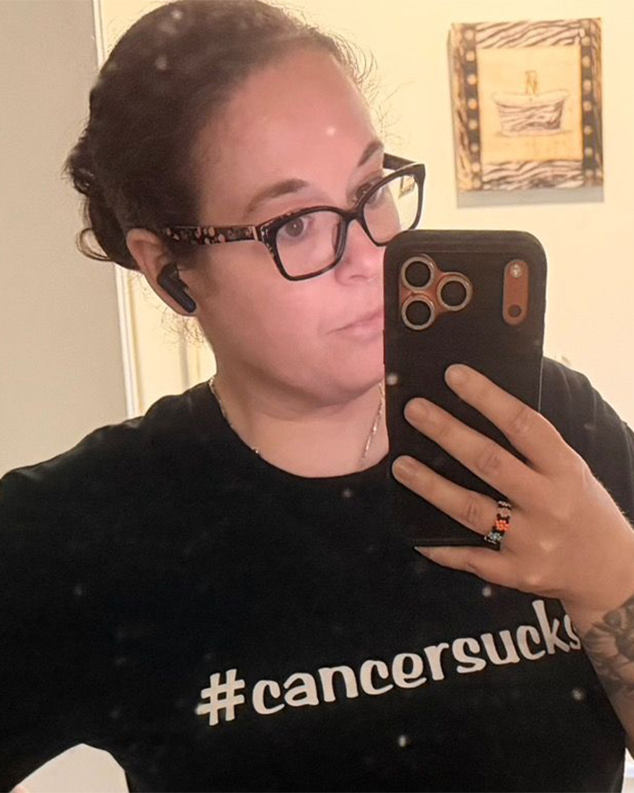 Terminally ill woman wearing #cancersucks shirt looking into a mirror, reflecting on an unexpected way to turn the tables. Terminally ill woman wearing #cancersucks shirt looking into a mirror, reflecting on an unexpected way to turn the tables.