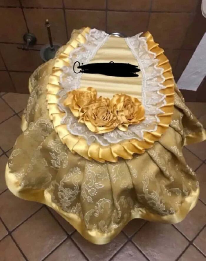 A toilet covered in an elaborate gold and lace fabric, with decorative roses, showcasing disturbing levels of skill.