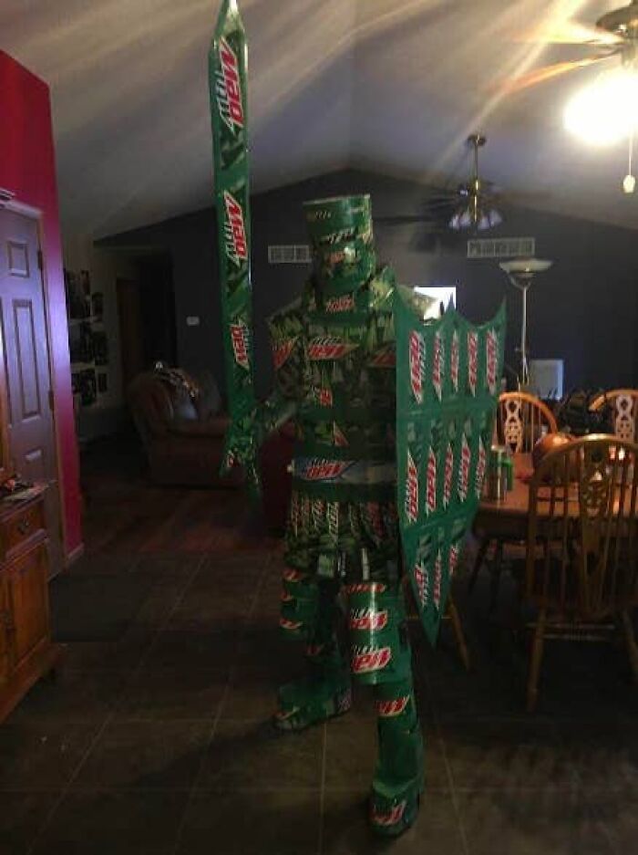 A person in a full suit of armor made from Mountain Dew cans, holding a sword and shield, displaying awful ideas.