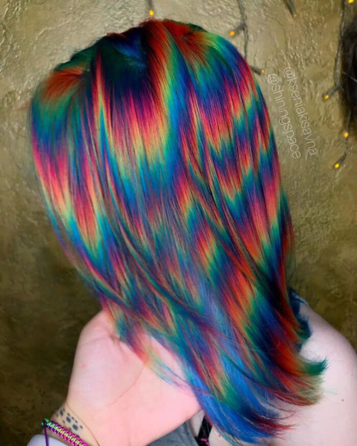 A person with disturbingly skillful rainbow-colored hair, displaying a vibrant and awful idea.