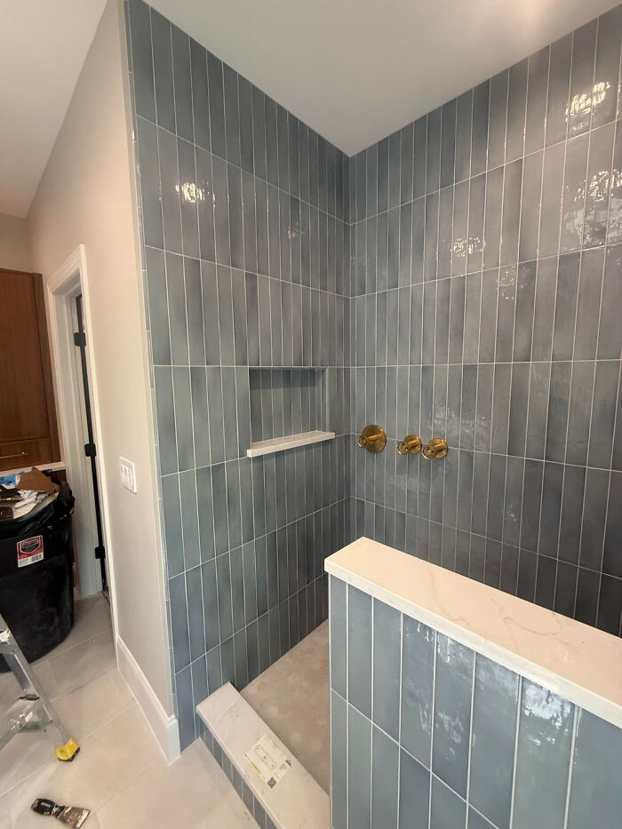 DIY home project featuring a modern shower renovation with sleek blue tiles and gold fixtures, transforming the space.