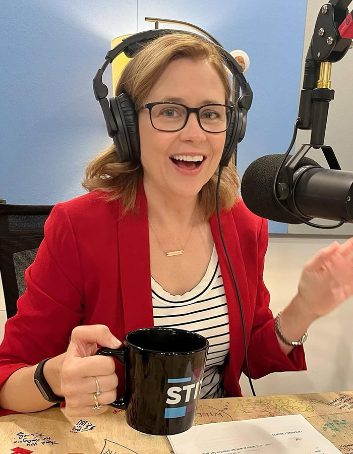 The Office star Jenna Fischer, wearing headphones and a red blazer, smiles while recording a podcast. The Office star Jenna Fischer, wearing headphones and a red blazer, smiles while recording a podcast.