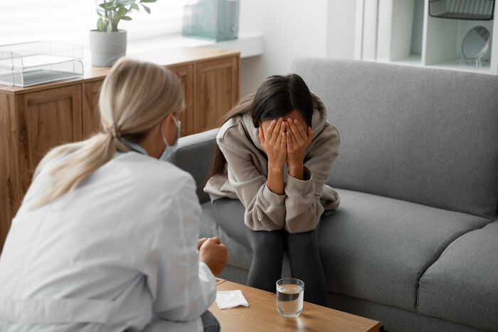 A woman crying with her face in her hands during a therapy session, highlighting mental health disorders.