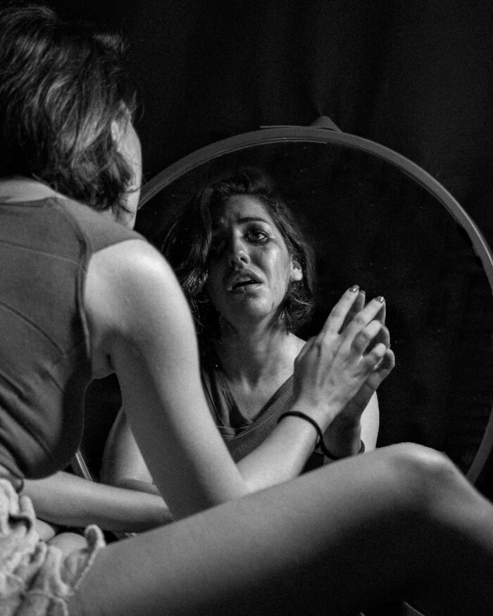 A woman cries while looking in a mirror, reflecting on the challenges of treating mental health disorders.