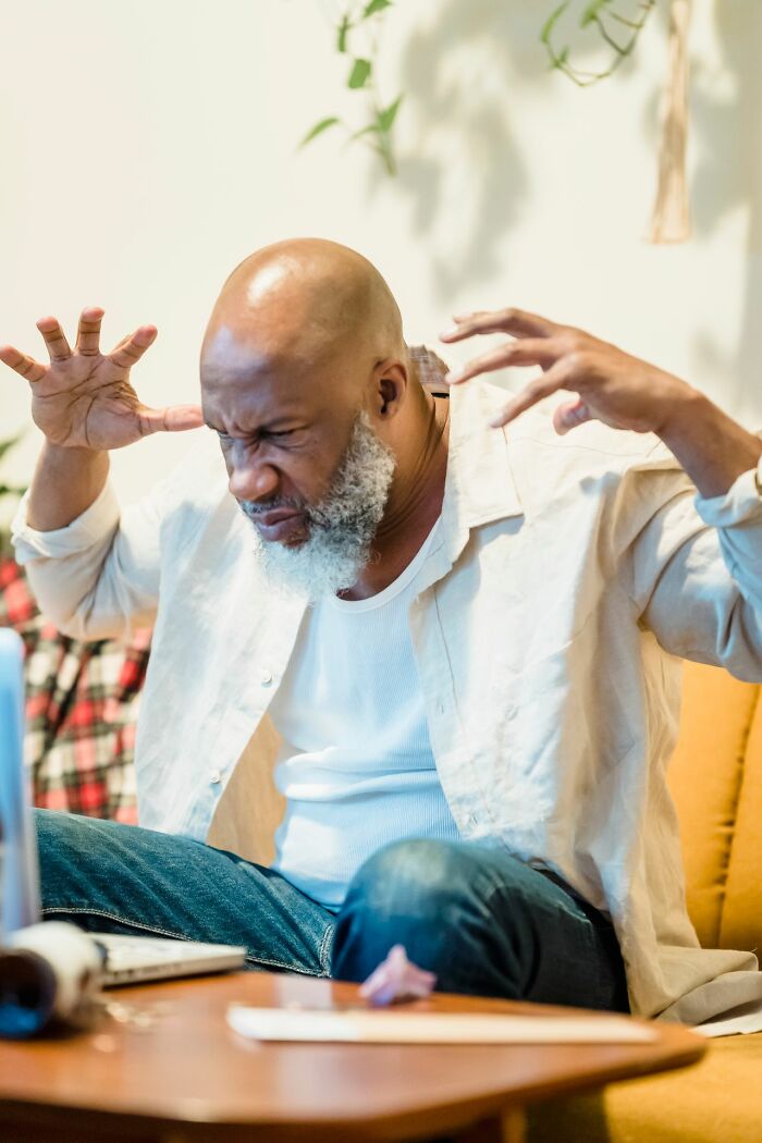 A man with a beard looking frustrated, hands near his head, representing the challenges of mental health disorders.