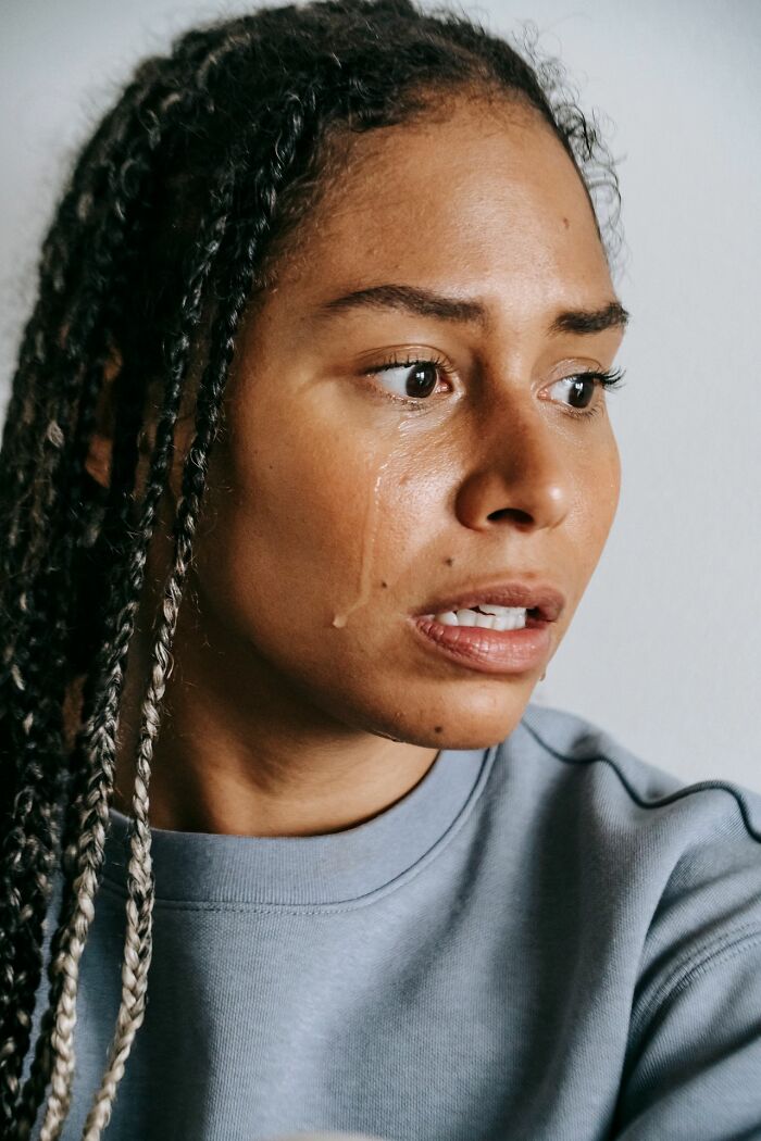 A woman with braided hair has tears streaming down her face, conveying the emotional toll of mental health disorders.