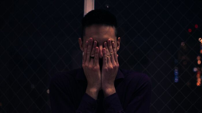 Man covering his face with hands, symbolizing the struggle with difficult to treat mental health disorders.