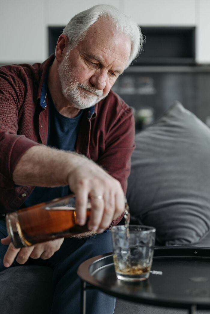 Elderly man pouring a drink, representing coping mechanisms for mental health disorders.