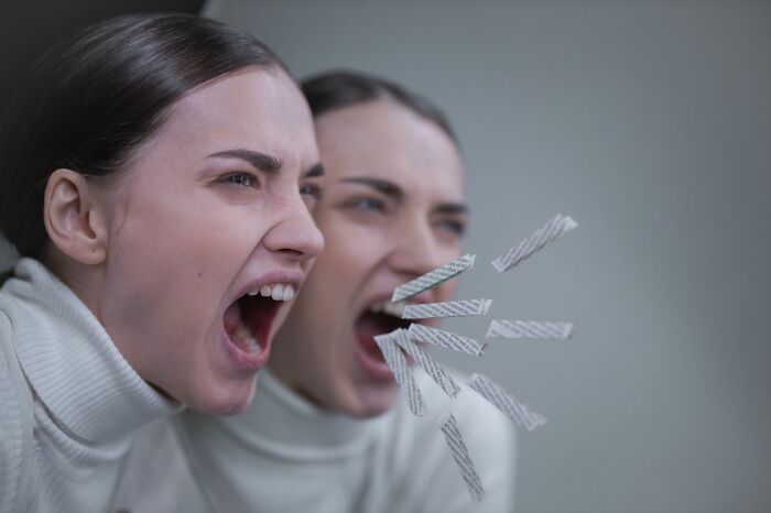 A woman screaming with pieces of paper flying from her mouth, symbolizing the challenges of mental health disorders.