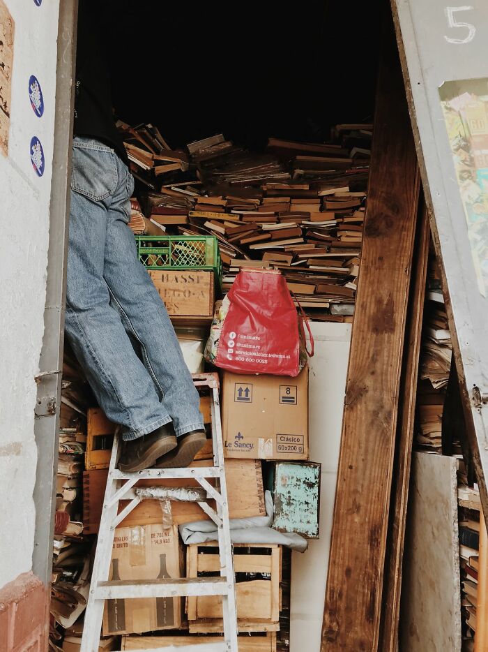 A person climbing a ladder in a room filled with books, representing the vast knowledge required to understand mental health disorders.