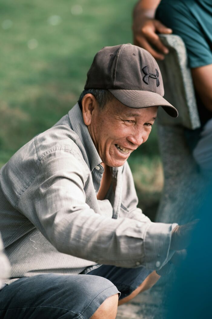A man in a baseball cap laughing outdoors, reflecting the welcoming and diverse experiences newcomers have in America.