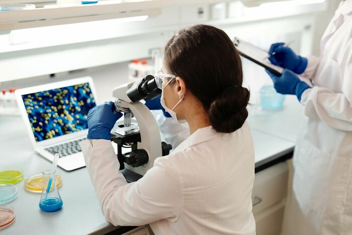 A woman scientist looking into a microscope in a lab, showcasing things America does better.