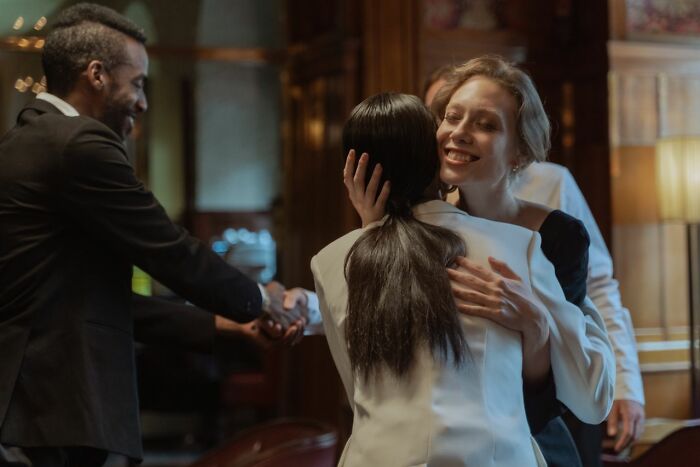 People sharing warm greetings and hugs, highlighting the welcoming aspect that America does better.