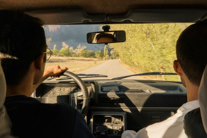Two people in a car driving on a scenic road, demonstrating things America does better.