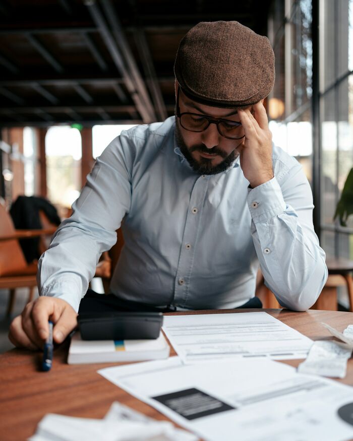 Man in a hat deeply focused on documents, highlighting America's dedication to detailed work.