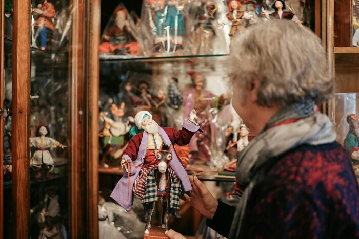Elderly woman examining a finely detailed doll representing America's unique cultural heritage.