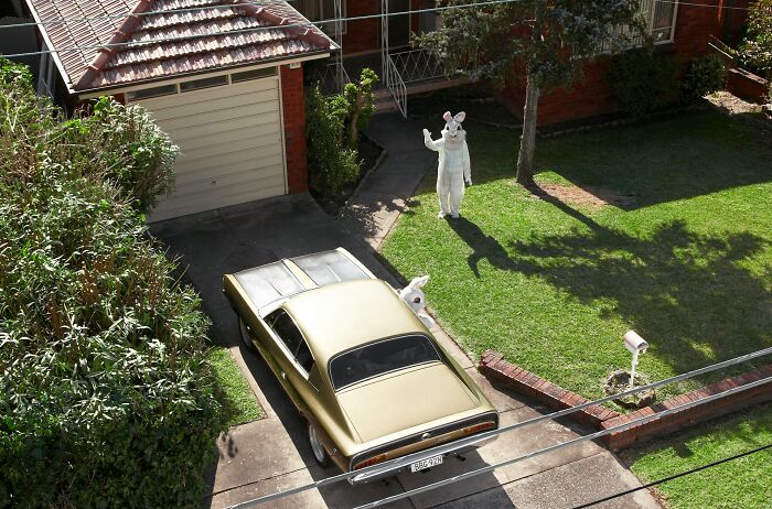 A person in an Easter bunny costume waving outside a house, showing things America does better.