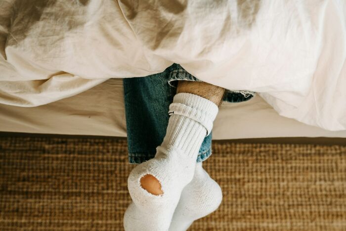 A person with a hole in their sock, illustrating a common poverty habit.