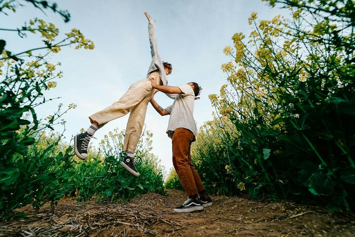 A joyful couple in a field of yellow flowers, with one person jumping high, embodying truths about being married.