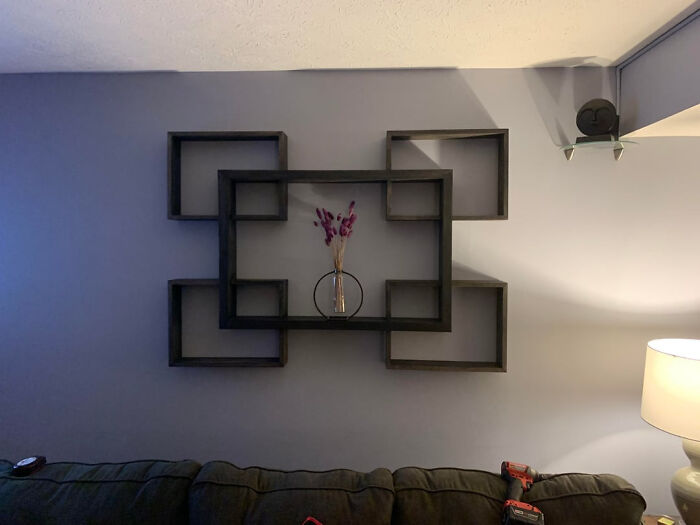 A geometric DIY home project wall shelf with interconnected square frames and a vase of dried flowers, illustrating you dont need a huge budget.