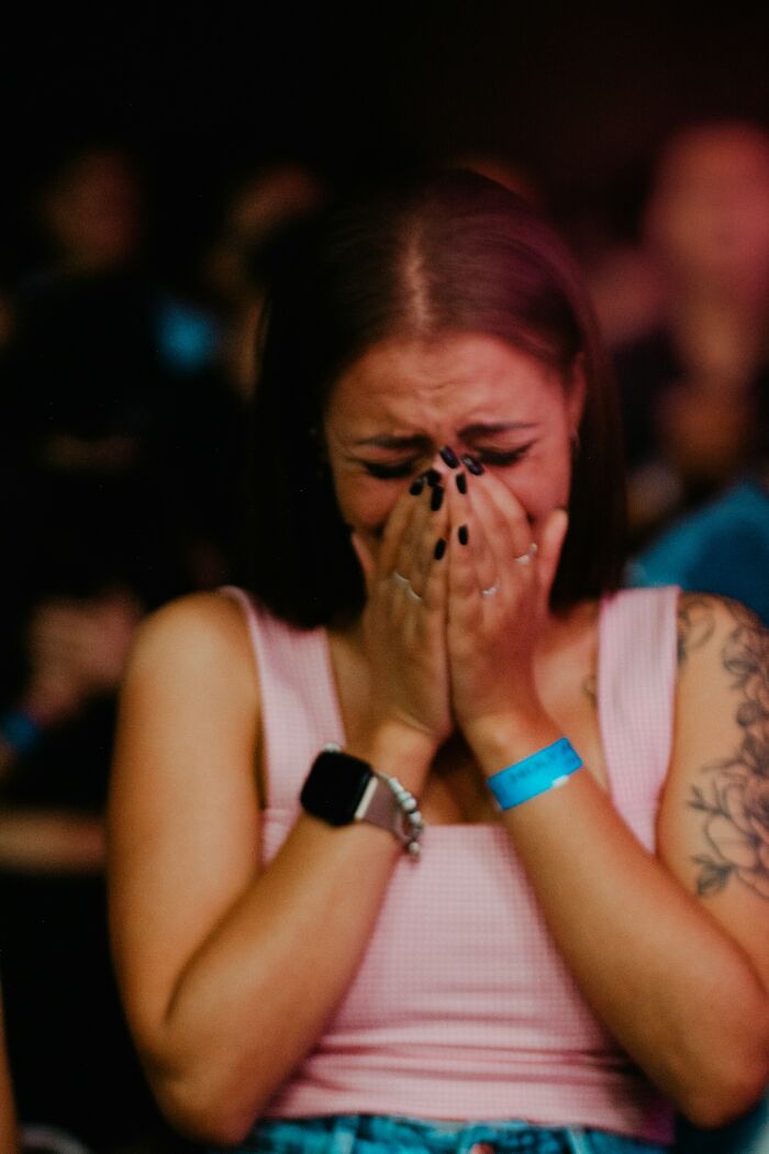 A woman crying with her hands covering her face, experiencing unbelievably scary and accurate true stories that question reality.