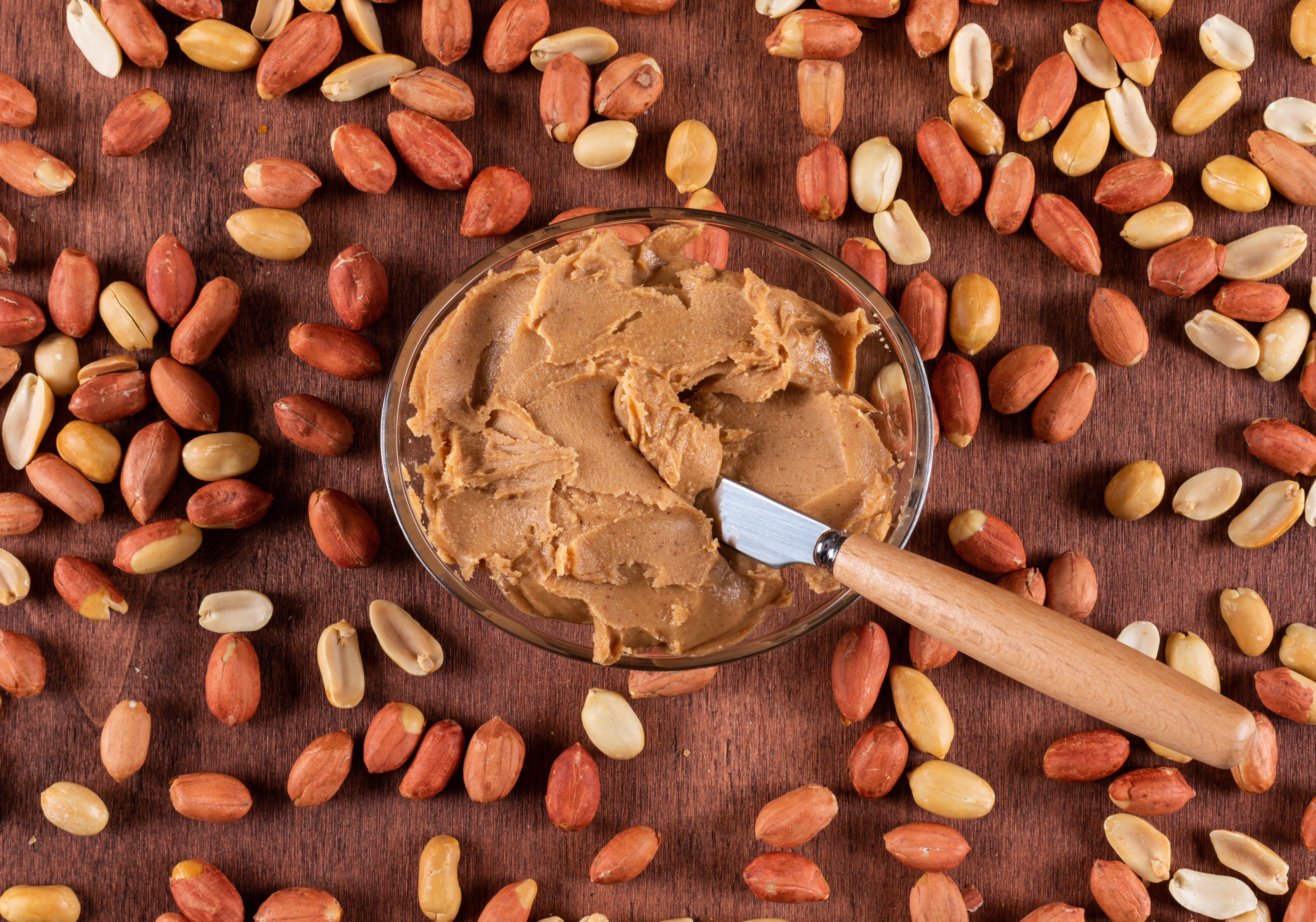 An overhead view of peanut butter in a bowl surrounded by peanuts, symbolizing the boyfriend forgetting his girlfriend's allergy. An overhead view of peanut butter in a bowl surrounded by peanuts, symbolizing the boyfriend forgetting his girlfriend's allergy.