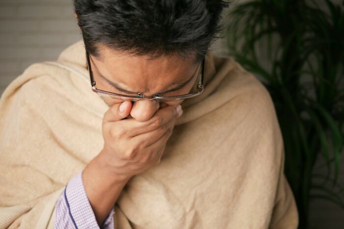 A man covers his mouth, looking unwell, conveying scary science facts about illness.