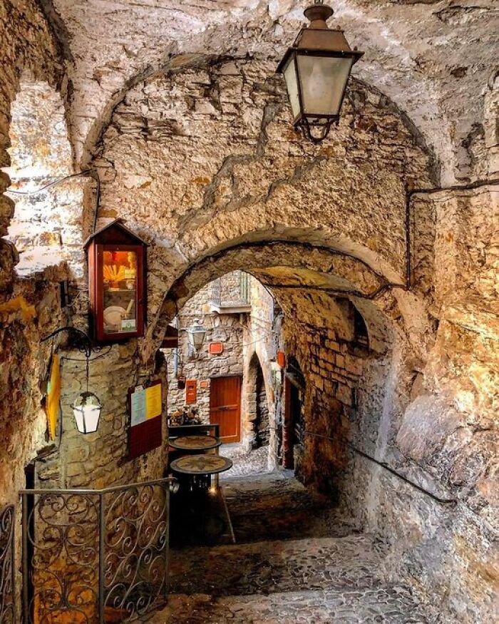 A narrow, ancient stone alleyway with arched ceilings and vintage lanterns, highlighting the character of old buildings.