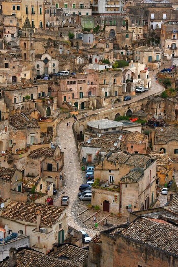 An aerial view of Matera, Italy, with ancient cave dwellings and buildings carved into the hillside, exuding historical character.