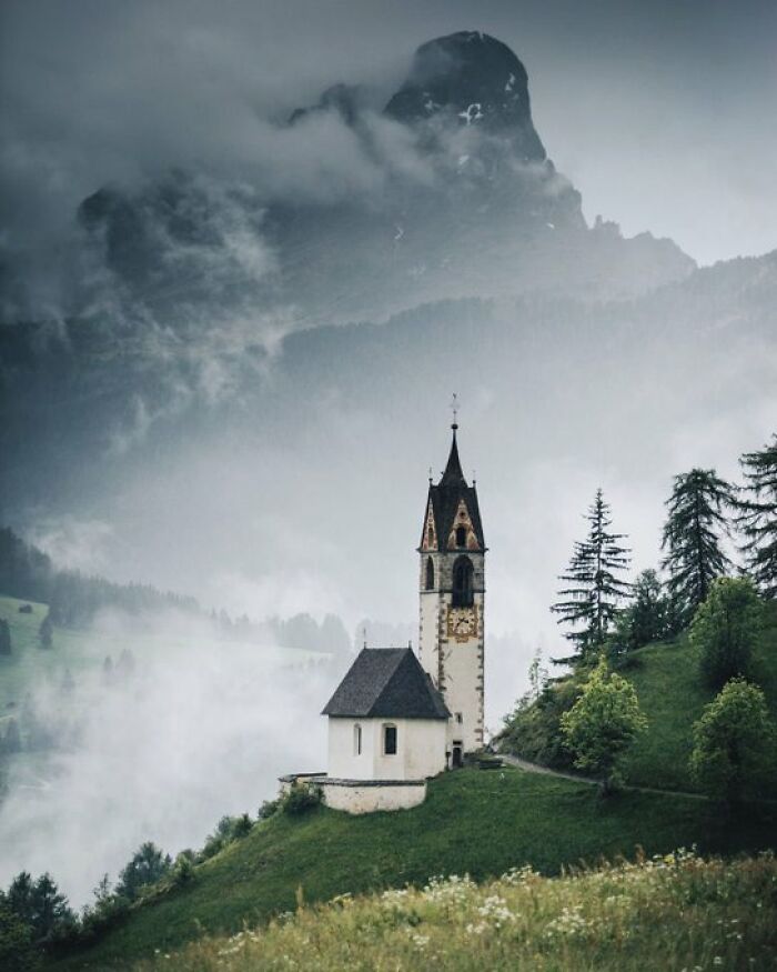 A charming old church on a misty mountainside, highlighting buildings with character in a dramatic landscape.