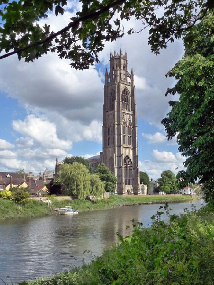 A towering old church with intricate designs by a tranquil river, highlighting the character of historical buildings.