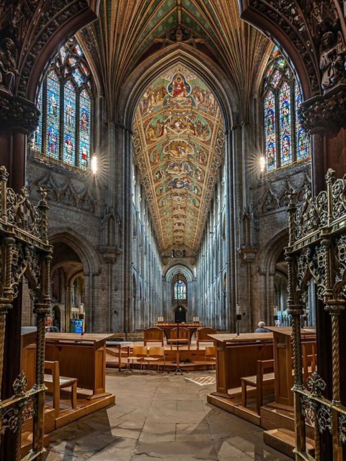 Interior of a grand cathedral showcasing its architectural character with stained glass and an ornate ceiling.