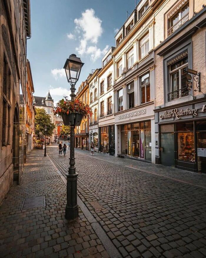 Cobblestone street lined with charming buildings and shops, a vintage lamppost in the foreground, exuding historical character.