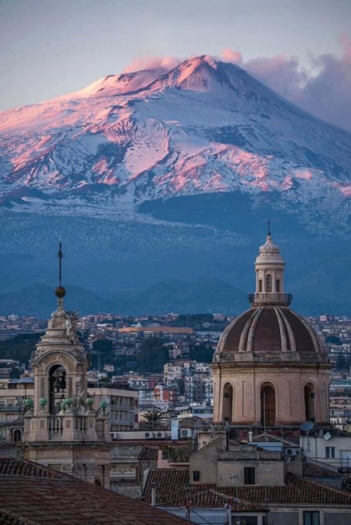 Cityscape featuring domed buildings with a snow-capped mountain in the background, displaying architectural and natural character.