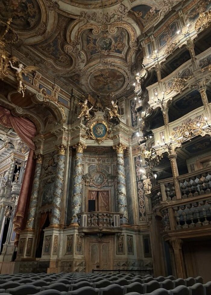 An exquisitely ornate opera house interior with detailed gold accents, frescoes, and balconies, displaying remarkable character in its design.
