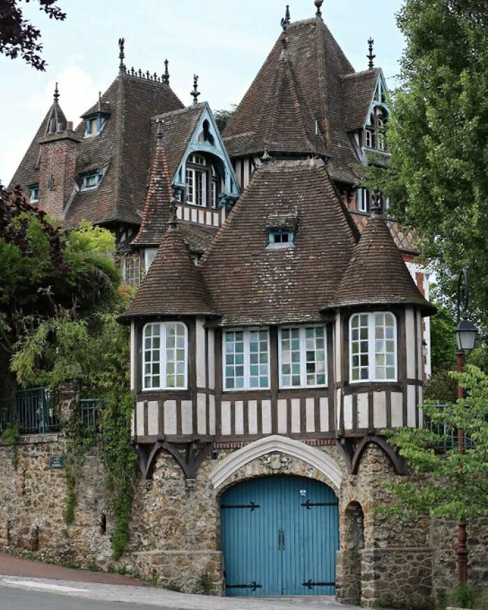 An enchanting, old-world building with multiple turrets, half-timbered walls, and a blue gate, showcasing architectural character.