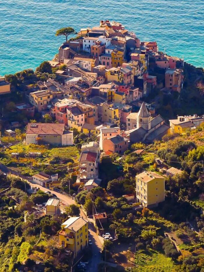 A picturesque coastal village featuring many colorful buildings cascading down a hill towards the vibrant blue sea, full of unique character.