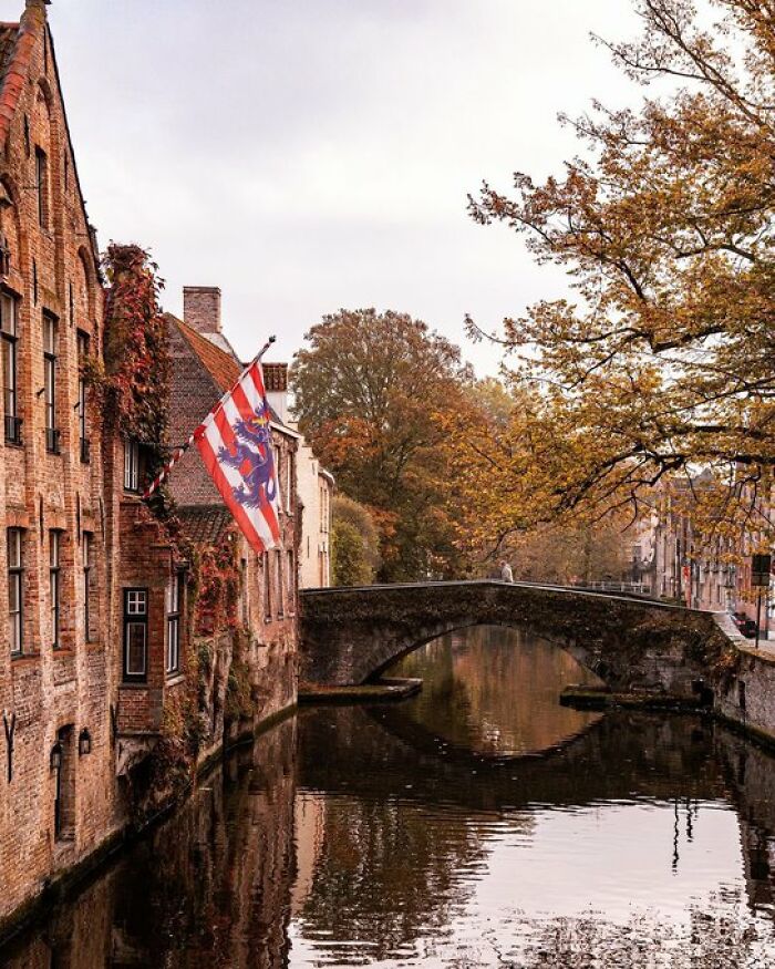 A serene canal scene with a stone bridge and historic brick buildings displaying so much character.