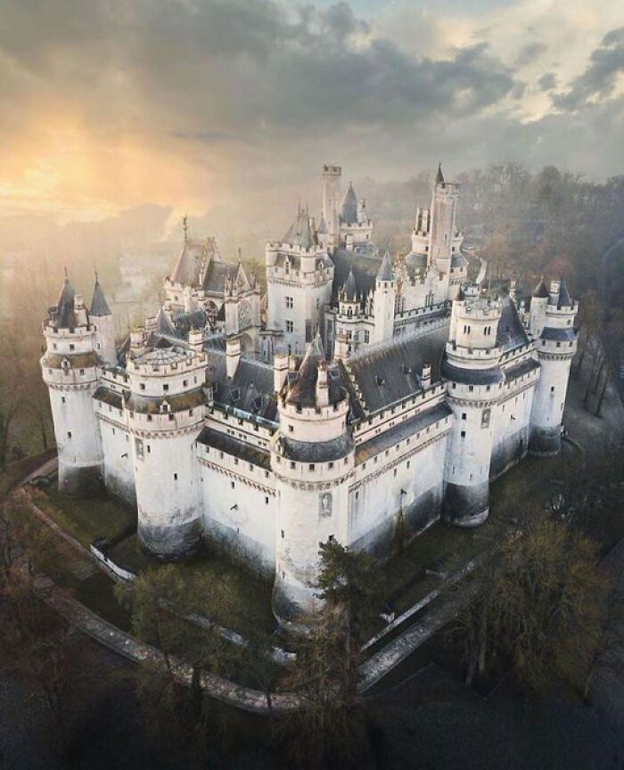 An aerial view of a majestic white castle with many turrets and buildings, showing its unique character.