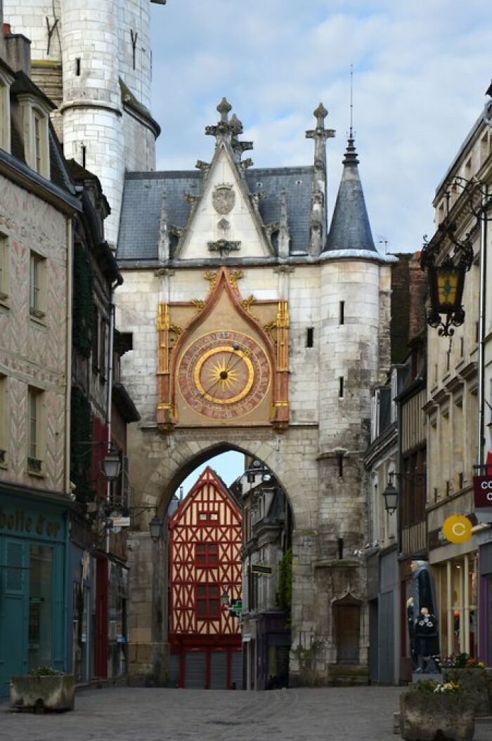 An ancient clock tower building with intricate details stands proudly over a cobblestone street, full of historical character.