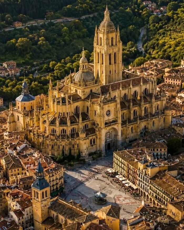 An aerial view of a grand, historic cathedral surrounded by old city buildings, demonstrating buildings with character.