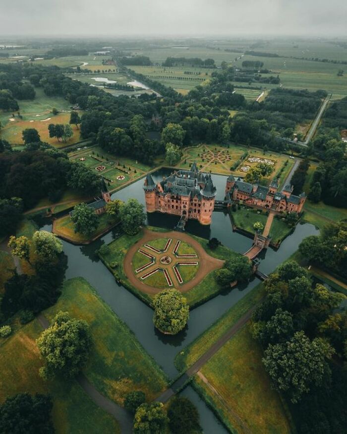 Aerial view of a stunning castle with moats and landscaped gardens, showcasing buildings with so much character.