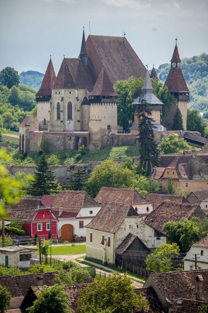 Historic fortified church atop a hill surrounded by traditional houses, highlighting buildings with so much character.