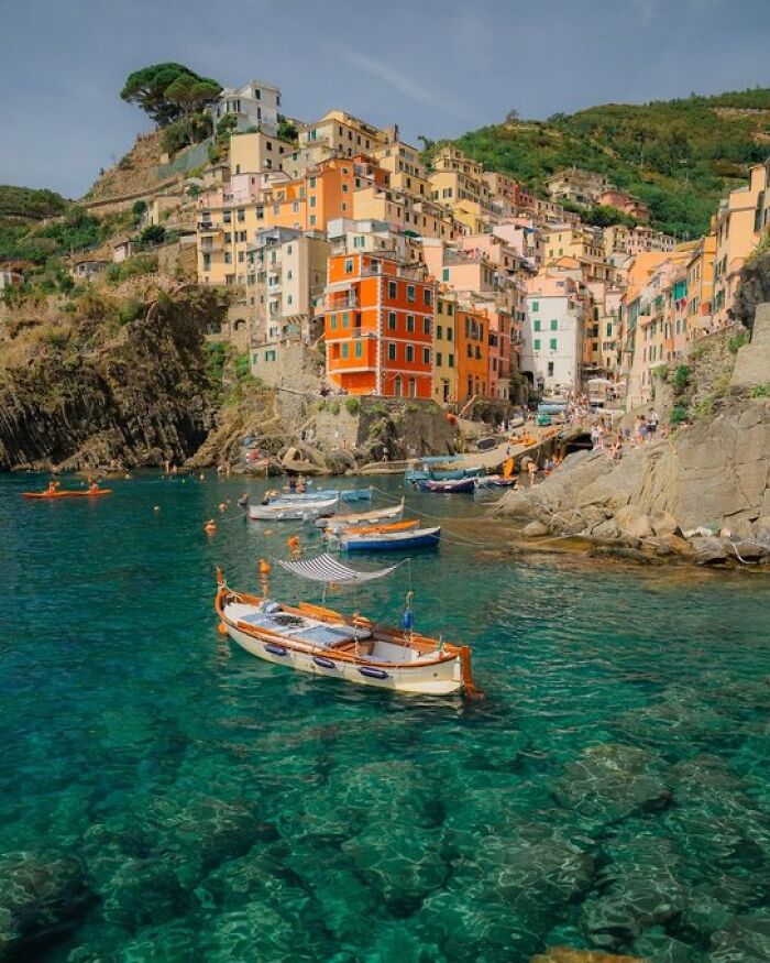 Vibrant, colorful buildings cascading down a cliffside to a clear blue bay, highlighting buildings with character.